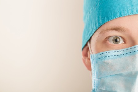 surprised male surgeon in mask looking at camera on grey background, close up. copy spaceの写真素材