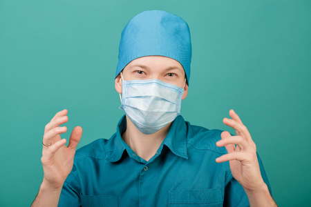 male surgeon in mask looking at camera on blue background, close upの写真素材