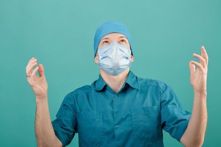 male surgeon in mask looking at camera on blue background, close upの写真素材