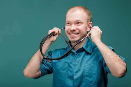 male doctor with stethoscope smiling on blue backgroundの写真素材
