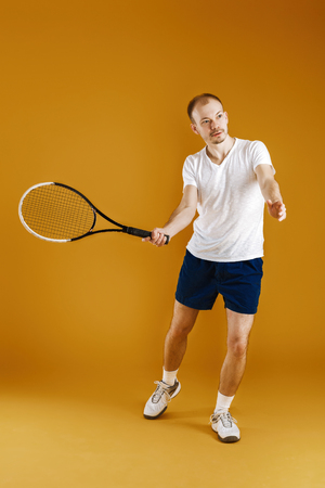 young tennis player plays tennis on yellow backgroundの写真素材