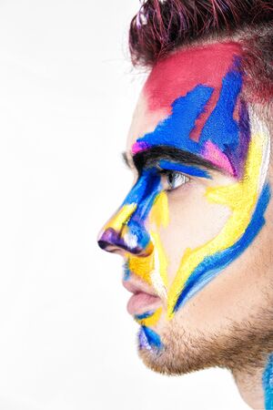 portrait of young attractive man with colored face paint on white background. Professional Makeup Fashion. ffantasy art makeupの写真素材
