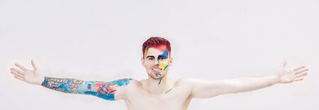 portrait of young attractive man with colored face paint on white background. Professional Makeup Fashion. ffantasy art makeupの写真素材