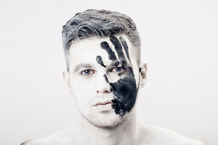 Young man with black hand print on white face. Closeup Portrait.  Professional Fashion Makeup. fantasy art  makeupの写真素材