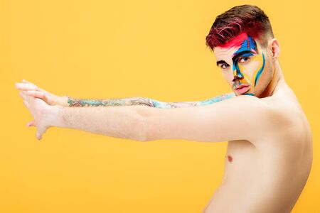 portrait of young man with colored face paint on yellow background. Professional Makeup Fashion. fantasy art makeupの写真素材