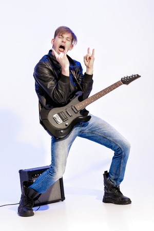 young expressive rock musician playing electric guitar and singing. Rock star making rock gestureの写真素材