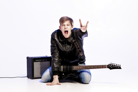 young expressive rock musician playing electric guitar and singing. Rock star making rock gesture