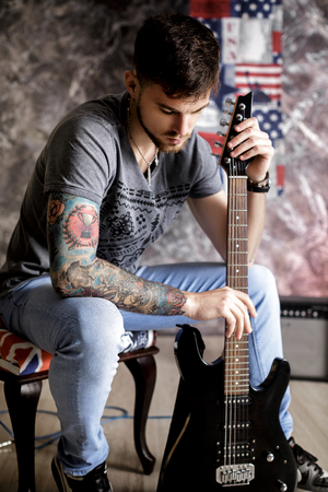 Young handsome musician with electric guitar on dark backgroundの写真素材