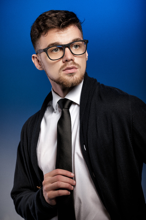 Portrait of handsome young man with glasses and white shirt on blue backgroundの写真素材