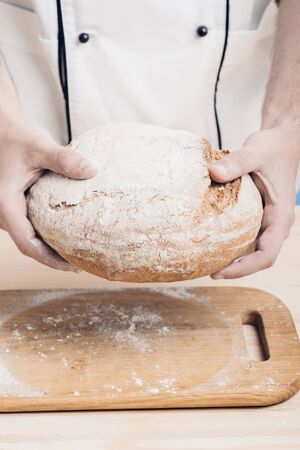 Fresh baked bread in  hands of  baker. soft light