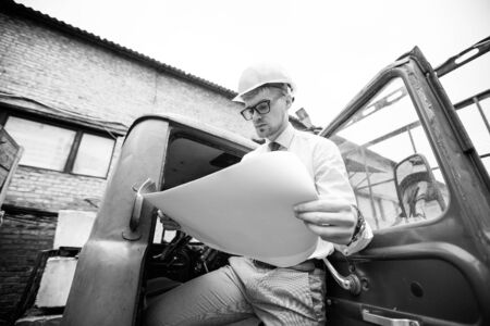 Engineer builder in a helmet holds drawings at  construction siteの写真素材