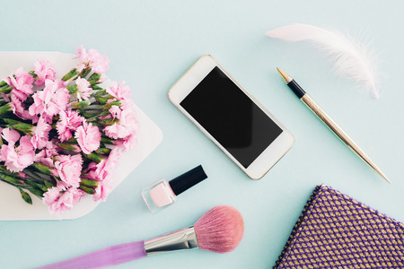 feminine flat lay on blue background, top view of womans desktop with  envelope, flowers, pen,  notepad and smartphone. mock upの写真素材