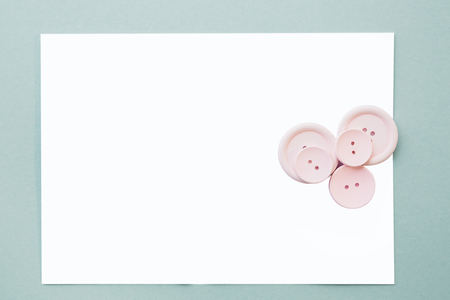 flat lay Pink buttons and a blank white sheet on a blue background, top view. mock upの写真素材