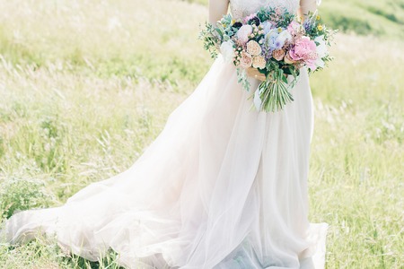 fine art wedding photography. Beautiful bride with bouquet and dress with train in natureの写真素材