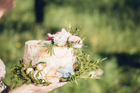 bride holding wedding cake. wedding cake decorated with flowersの写真素材
