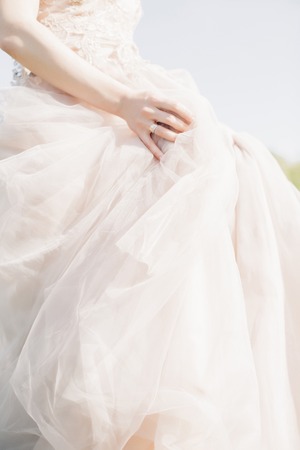 Hands of bride on wedding dress on sunny day. fine art photography.の写真素材