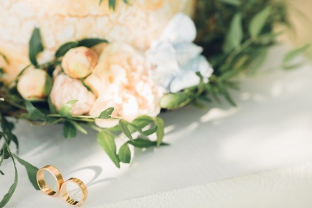 Two wedding rings on wedding cake backgroundの写真素材