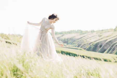 fine art wedding photography. Beautiful bride with bouquet and dress with train in natureの写真素材