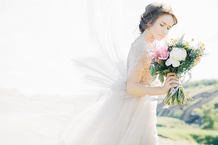 fine art wedding photography. Beautiful bride with bouquet and dress with train in natureの写真素材