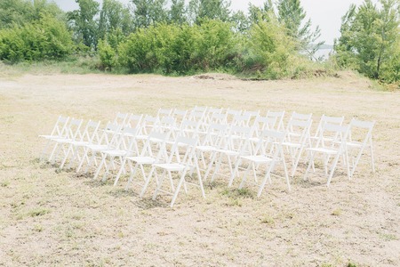 Many rows of white wooden chairs for wedding ceremony in natureの写真素材