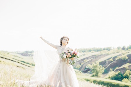 fine art wedding photography. Beautiful bride with bouquet and dress with train in natureの写真素材