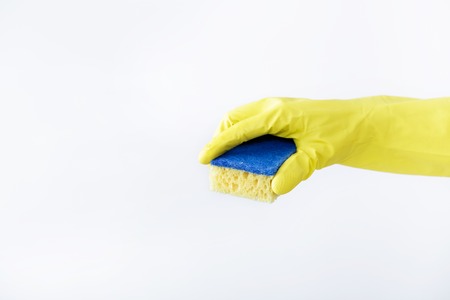 hand in rubber yellow glove holding sponge on white background. cleaningの写真素材