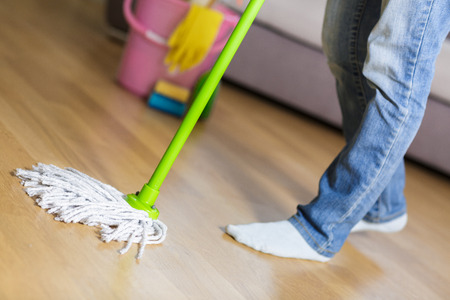 woman in protective gloves using a wet-mop while cleaning floorの写真素材
