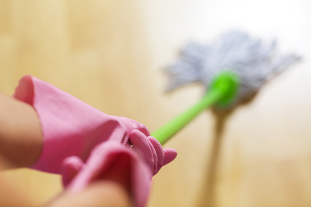 woman in protective gloves using a wet-mop while cleaning floorの写真素材