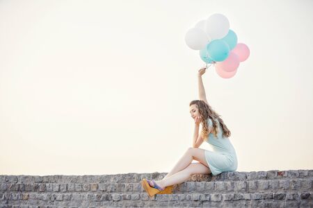 beautiful woman with flying multicolored balloonsの写真素材