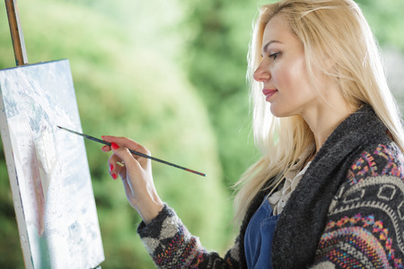 woman artist with a brush in her hand draws on canvasの写真素材