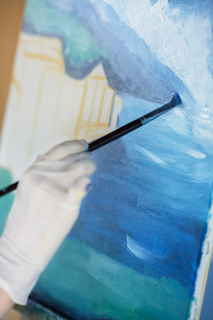 artists hand with brush painting on canvasの写真素材