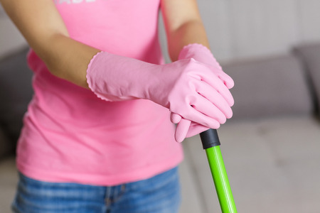 woman in protective gloves using a wet-mop while cleaning floor