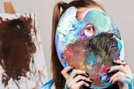 woman artistholds  palette with paints in front of faceの写真素材