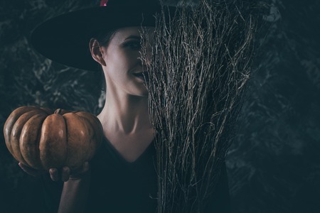 Halloween Witch holding a pumpkin and a broom.の写真素材