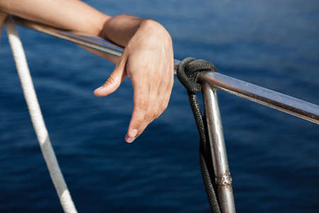 hand on railing of yacht against  background of seaの写真素材
