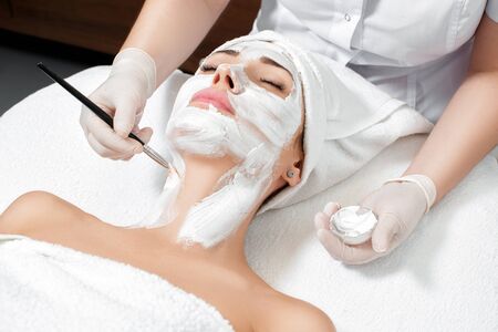 beautician applies mask to the face of  woman