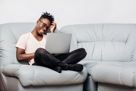 man in glasses sitting with laptop on sofaの写真素材