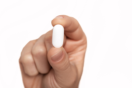 pill in mans hand on white background