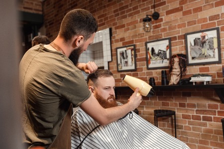Barber and bearded man in barber shopの写真素材