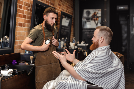 Barber and bearded man in barber shopの写真素材