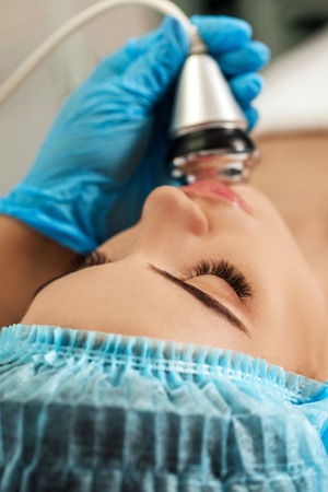 Beautician makes cleaning of face in spa salon.の写真素材