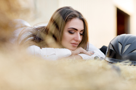 rider woman with whip is sitting on hayの写真素材
