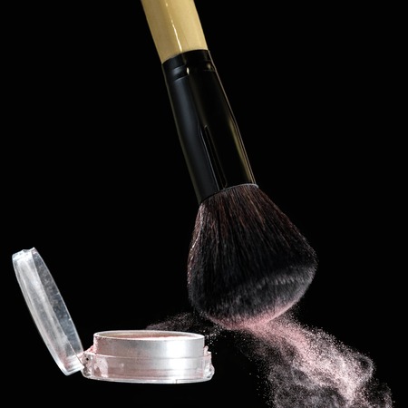 Make up brush with powder splashes on black backgroundの写真素材