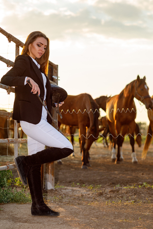 rider woman with whip at the sunsetの写真素材