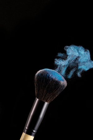 Make up brush with powder splashes on black backgroundの写真素材