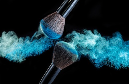 Make up brush with blue powder splashes on black background. blue powder explosionの写真素材