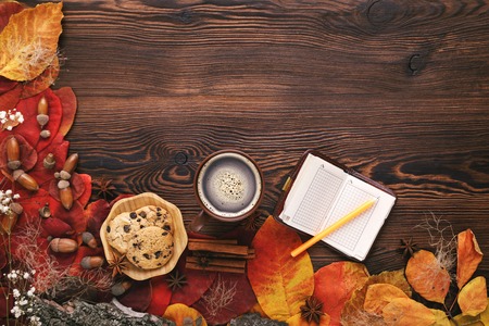 autumn leaves, cookies and paper notebook on wooden background