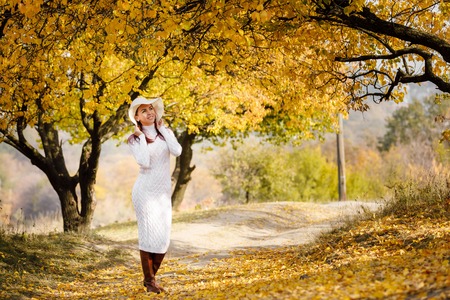 woman in dress and hat on background of autumn foliageの写真素材