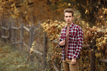 Handsome young guy in nature on an autumn dayの写真素材