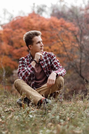 Handsome young guy in nature on an autumn dayの写真素材
